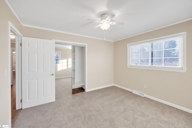 unfurnished bedroom featuring ceiling fan, crown molding, light carpet, and multiple windows