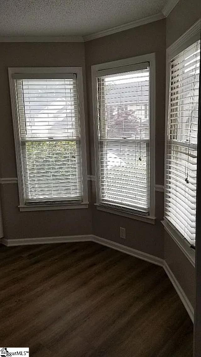 empty room featuring a textured ceiling, hardwood / wood-style flooring, and ornamental molding