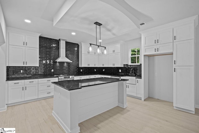 kitchen with white cabinets, pendant lighting, wall chimney exhaust hood, and light hardwood / wood-style floors