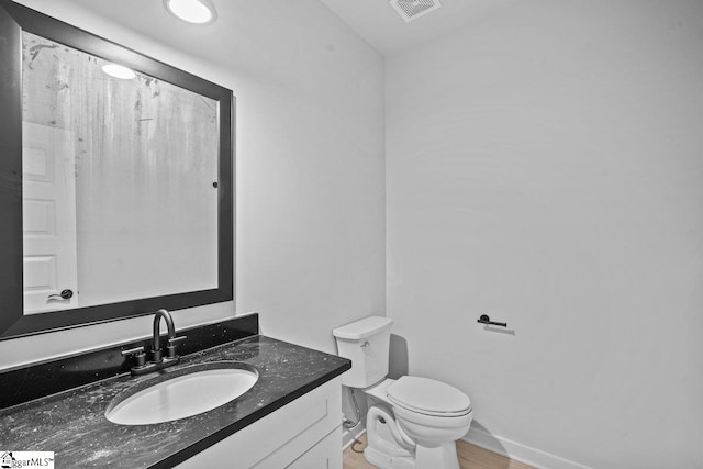 bathroom featuring toilet, vanity, and hardwood / wood-style flooring