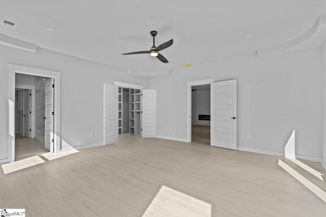 interior space featuring ceiling fan, a spacious closet, light wood-type flooring, connected bathroom, and a closet