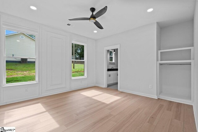 unfurnished bedroom featuring ceiling fan, light wood-type flooring, ensuite bathroom, and a closet