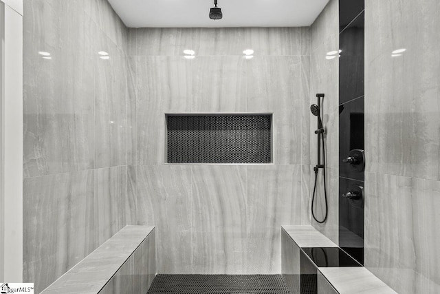 bathroom featuring tiled shower and tile walls