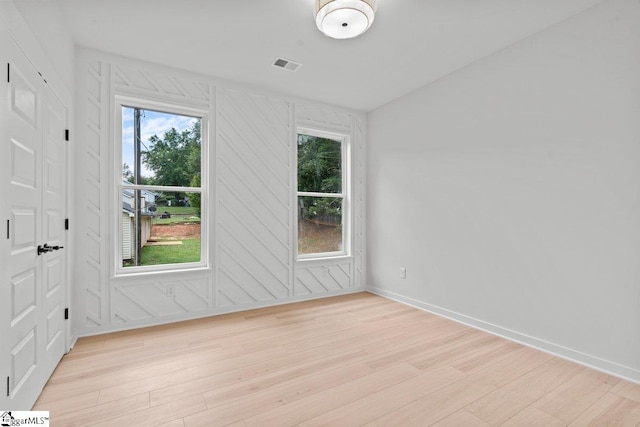 spare room featuring light wood-type flooring and wooden walls