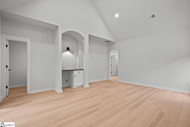 unfurnished bedroom featuring high vaulted ceiling and light wood-type flooring