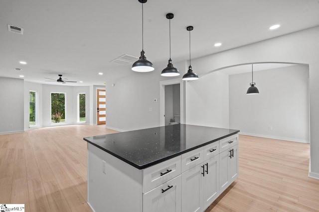 kitchen with light wood-type flooring, white cabinetry, hanging light fixtures, and ceiling fan