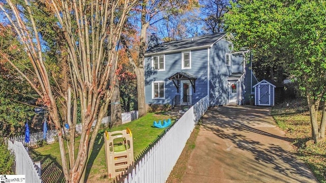 view of front of home with a front yard and a storage shed