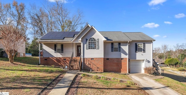 view of front of house featuring covered porch, solar panels, a garage, and a front yard