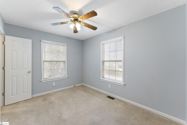 carpeted spare room featuring ceiling fan, a healthy amount of sunlight, and a textured ceiling