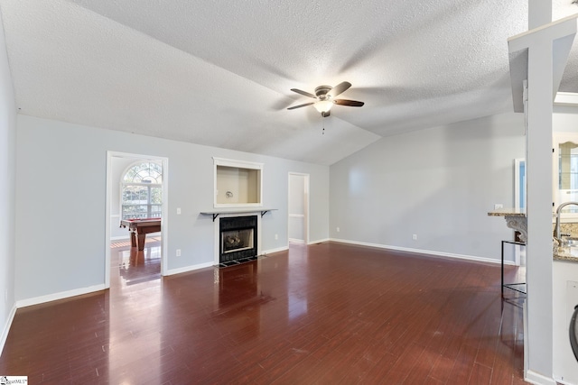 unfurnished living room with billiards, vaulted ceiling, ceiling fan, a textured ceiling, and dark hardwood / wood-style flooring