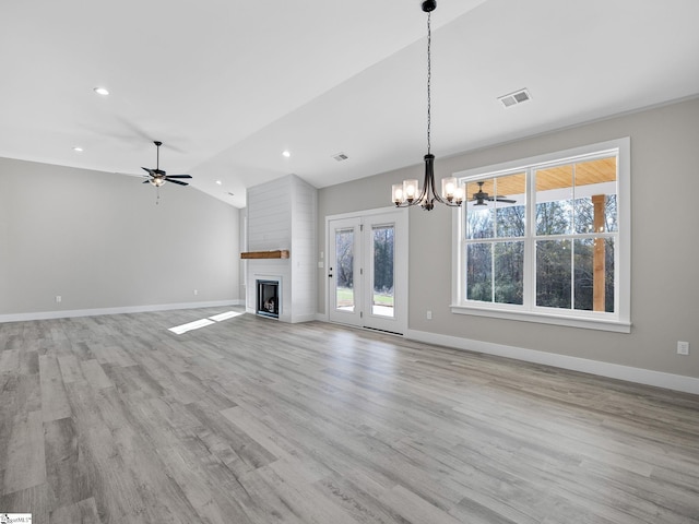 unfurnished living room featuring a large fireplace, light hardwood / wood-style flooring, ceiling fan with notable chandelier, and lofted ceiling