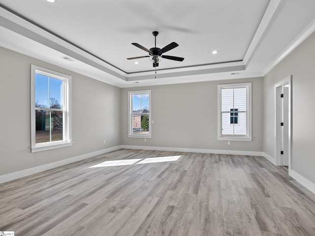 spare room featuring light hardwood / wood-style flooring, a raised ceiling, and ceiling fan