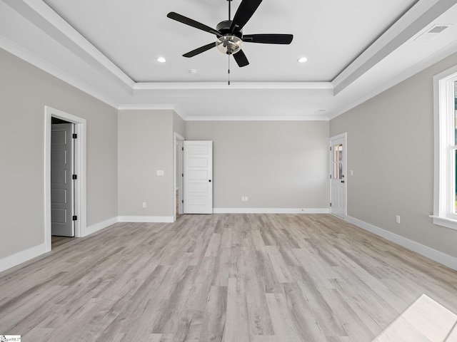 empty room with a raised ceiling, ceiling fan, light hardwood / wood-style floors, and ornamental molding