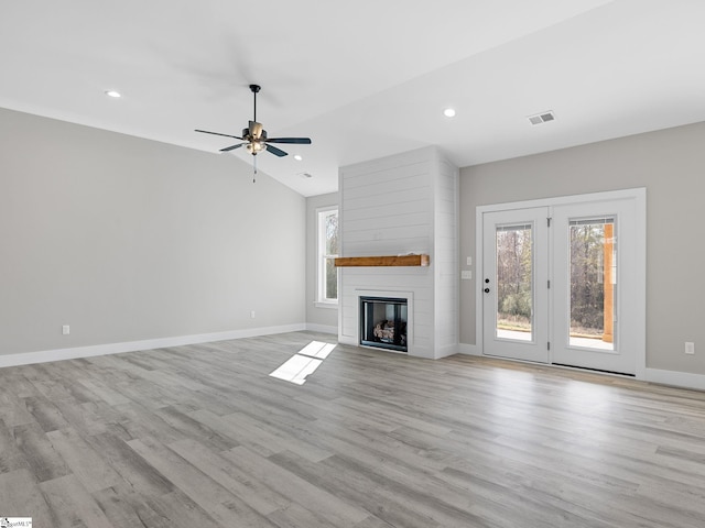 unfurnished living room featuring ceiling fan, a large fireplace, vaulted ceiling, and light hardwood / wood-style flooring