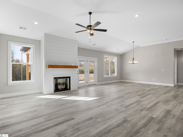 unfurnished living room featuring a large fireplace, light hardwood / wood-style flooring, ceiling fan with notable chandelier, and lofted ceiling