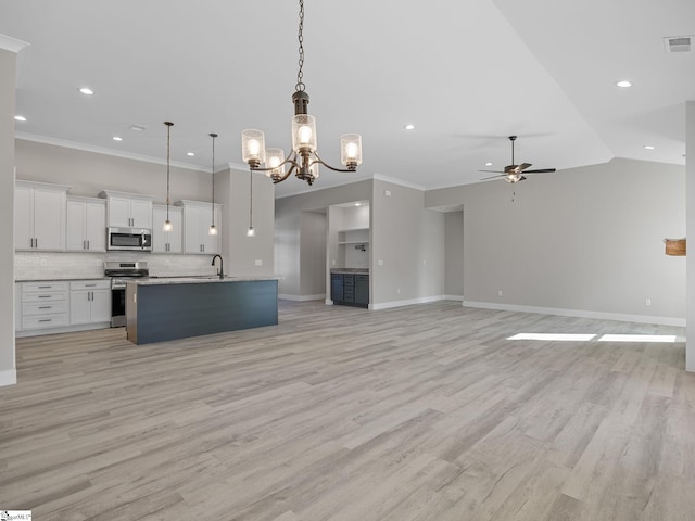 kitchen featuring light wood-type flooring, stainless steel appliances, white cabinets, hanging light fixtures, and an island with sink