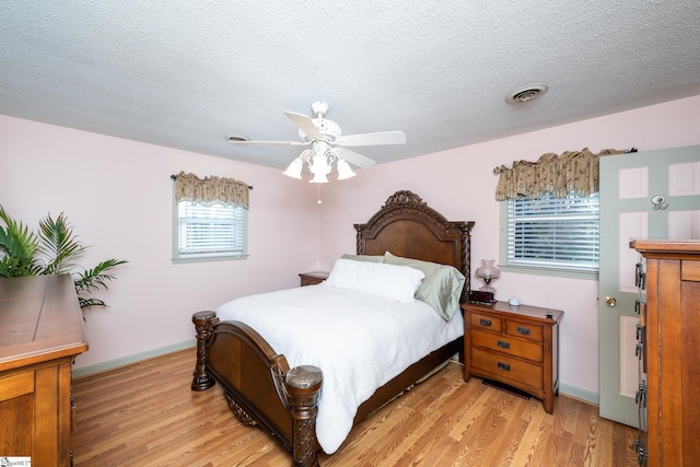 bedroom featuring ceiling fan, light hardwood / wood-style flooring, and a textured ceiling