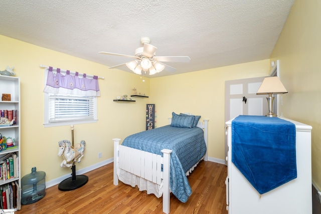 bedroom with ceiling fan, wood-type flooring, and a textured ceiling