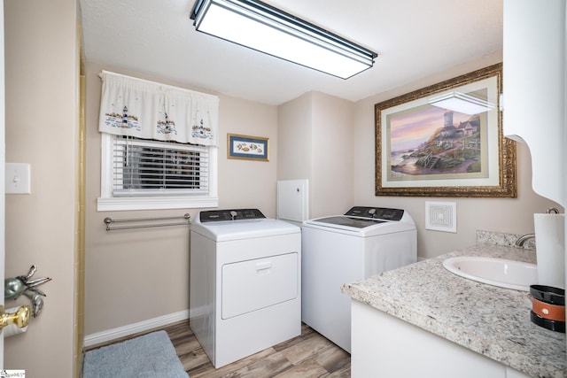 laundry room featuring sink, washer and dryer, and light wood-type flooring