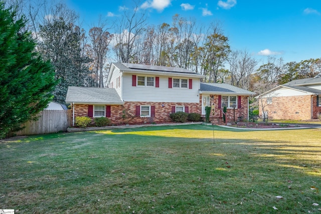 tri-level home with a front lawn and solar panels