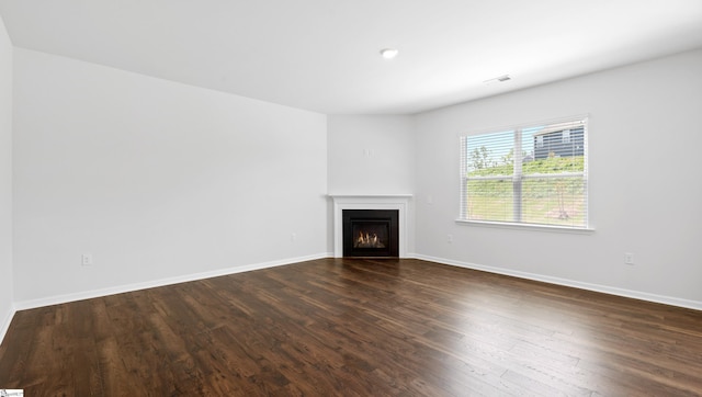 305 Lodestone Rd Lot 0267, Simpsonville, SC 29680 - unfurnished living room with a warm lit fireplace, dark wood-type flooring, visible vents, and baseboards