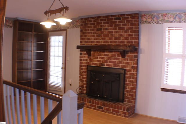 unfurnished living room featuring wood-type flooring and a brick fireplace