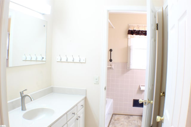 bathroom with tile patterned flooring, vanity, a washtub, and tile walls