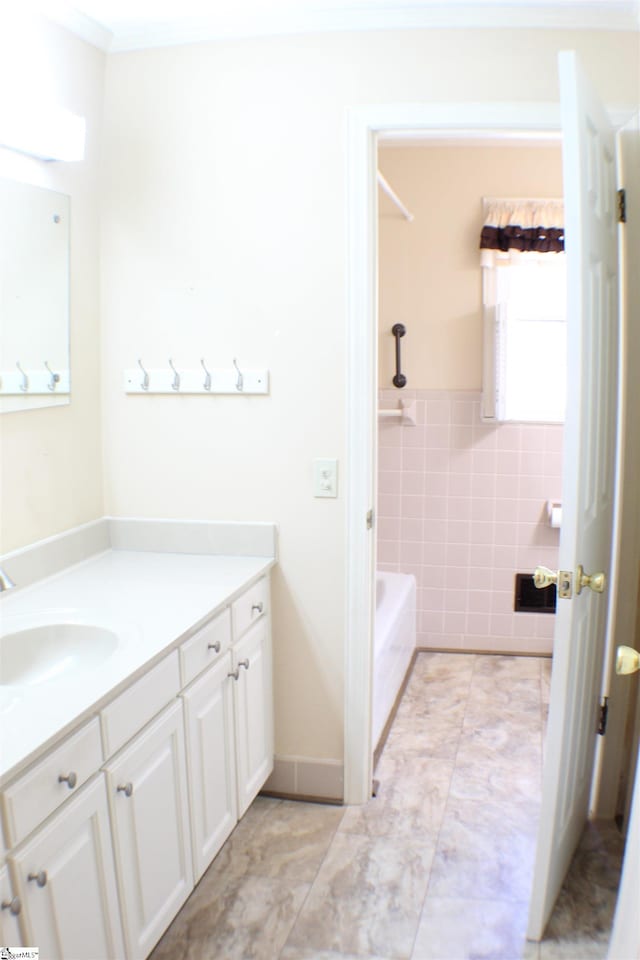 bathroom with crown molding, vanity, tile walls, and a washtub