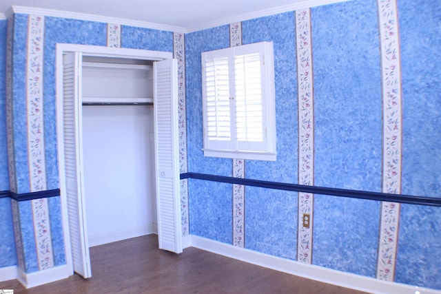 unfurnished bedroom featuring dark wood-type flooring, ornamental molding, and a closet