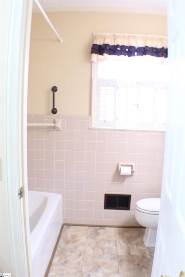 bathroom featuring toilet, tile patterned flooring, and tile walls