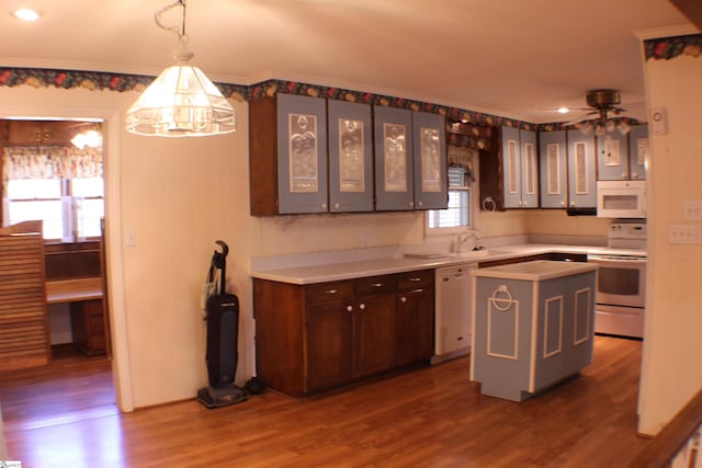 kitchen with hardwood / wood-style floors, sink, hanging light fixtures, a center island, and white appliances