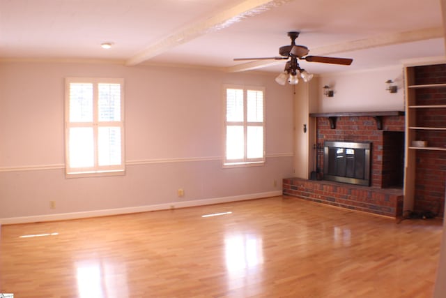 unfurnished living room with a fireplace, beamed ceiling, hardwood / wood-style flooring, ornamental molding, and ceiling fan