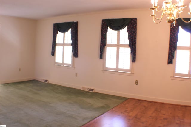 empty room featuring crown molding, carpet, a wealth of natural light, and a notable chandelier