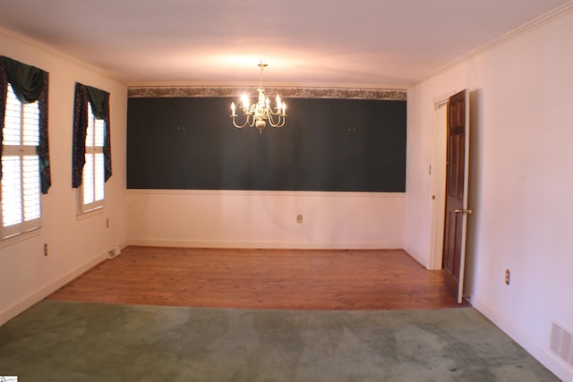 carpeted spare room featuring an inviting chandelier and crown molding