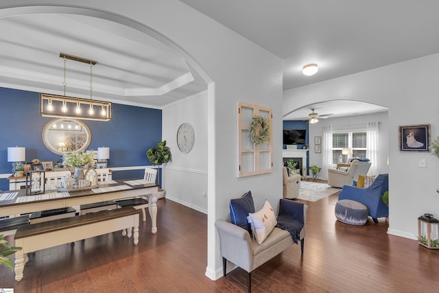 dining space featuring dark hardwood / wood-style floors, ceiling fan, ornamental molding, and a tray ceiling