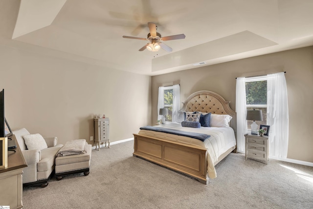 bedroom with a tray ceiling, ceiling fan, and carpet floors