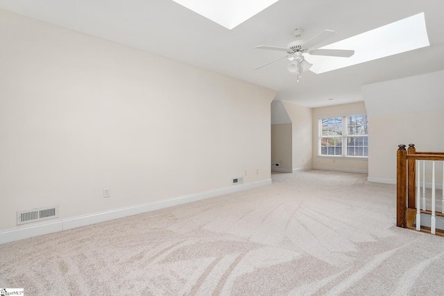 additional living space with ceiling fan, light carpet, and a skylight