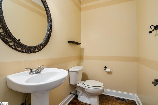 bathroom with wood-type flooring, toilet, and sink