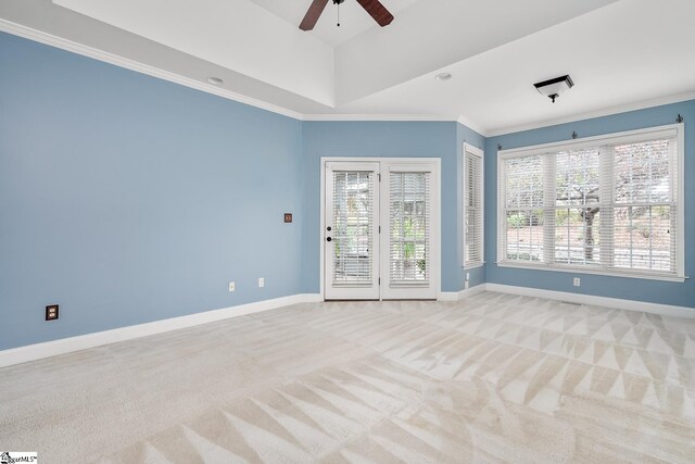 carpeted empty room featuring ceiling fan, ornamental molding, and a wealth of natural light