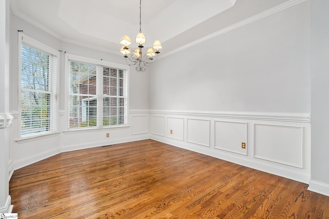 unfurnished room with hardwood / wood-style flooring, crown molding, a tray ceiling, and an inviting chandelier