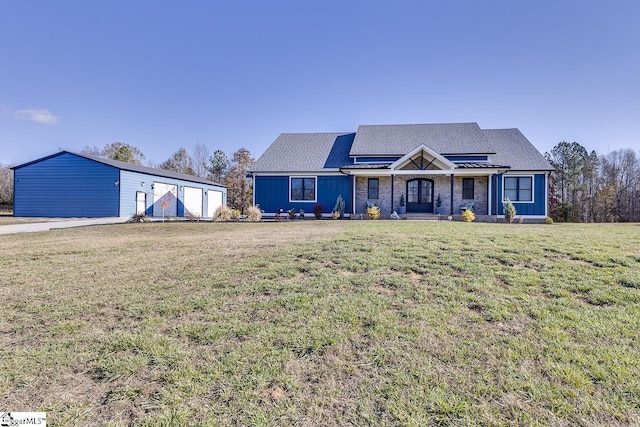 view of front of home featuring a porch, a garage, an outbuilding, and a front lawn