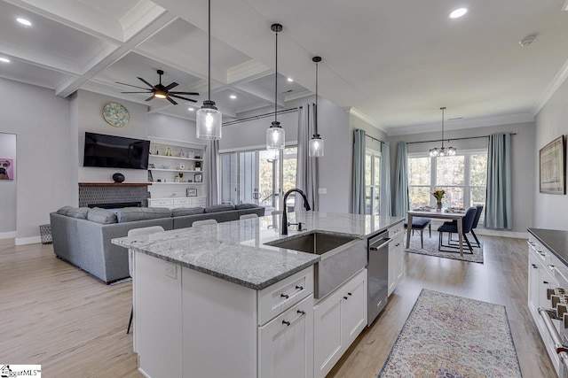 kitchen featuring dishwasher, a kitchen island with sink, white cabinets, sink, and a fireplace