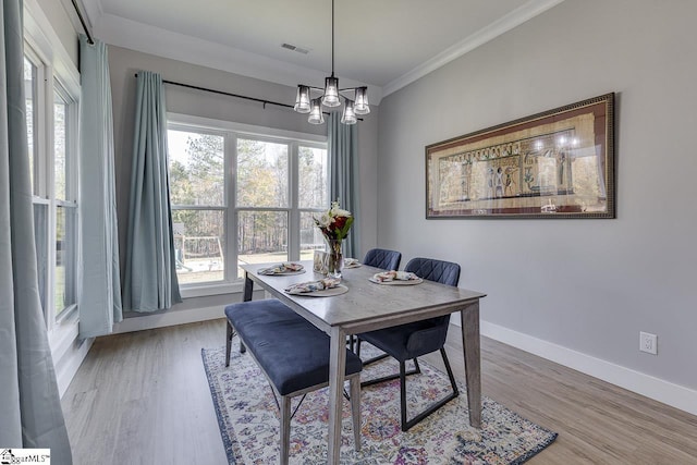 dining space featuring ornamental molding, wood-type flooring, and a notable chandelier