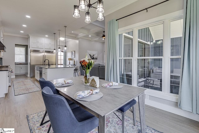 dining space with coffered ceiling, beamed ceiling, light hardwood / wood-style floors, ceiling fan with notable chandelier, and ornamental molding