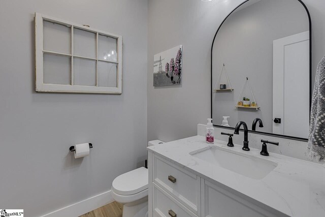 bathroom featuring wood-type flooring, vanity, and toilet