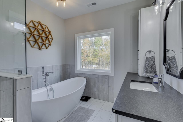 bathroom featuring a washtub, tile walls, and vanity