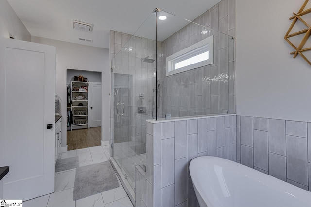 bathroom featuring tile walls and independent shower and bath