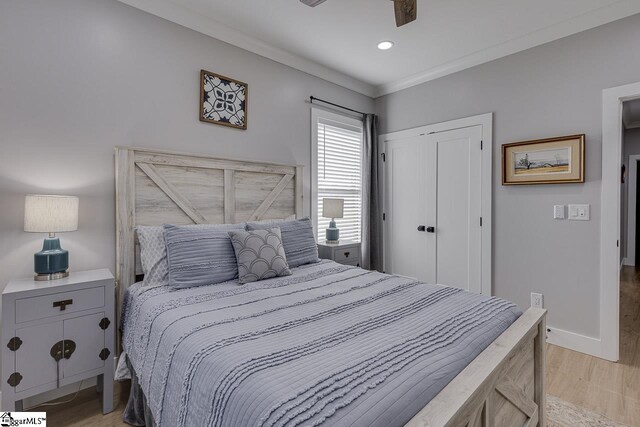 bedroom featuring light hardwood / wood-style flooring, a closet, ornamental molding, and ceiling fan