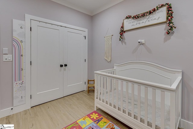 bedroom featuring a closet, hardwood / wood-style flooring, and a nursery area