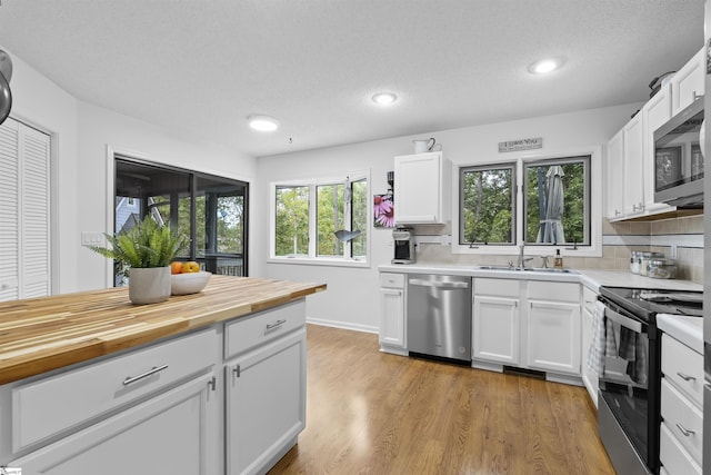 kitchen with stainless steel appliances, white cabinetry, and plenty of natural light